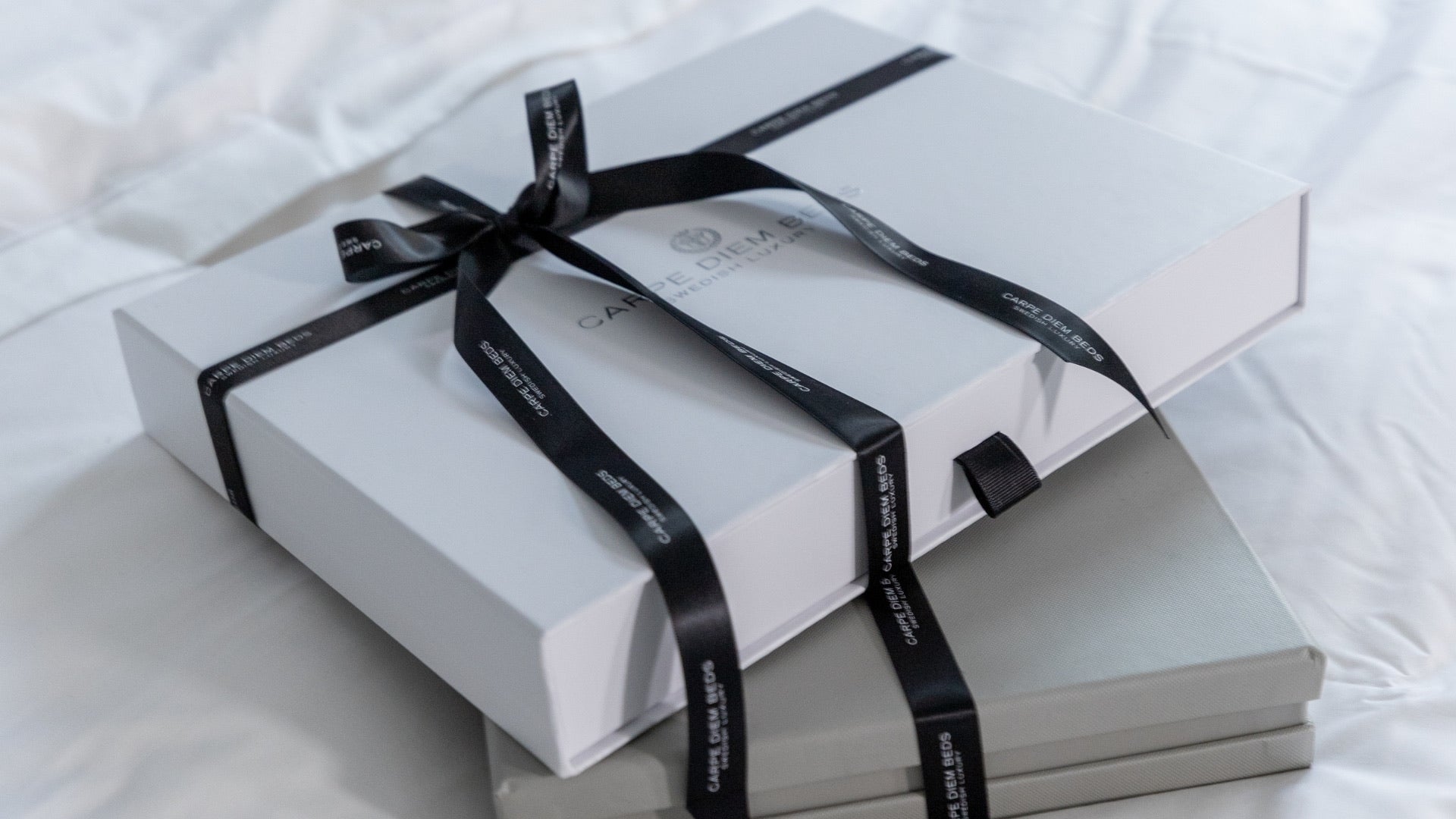 Two books tied with a black ribbon on a white surface