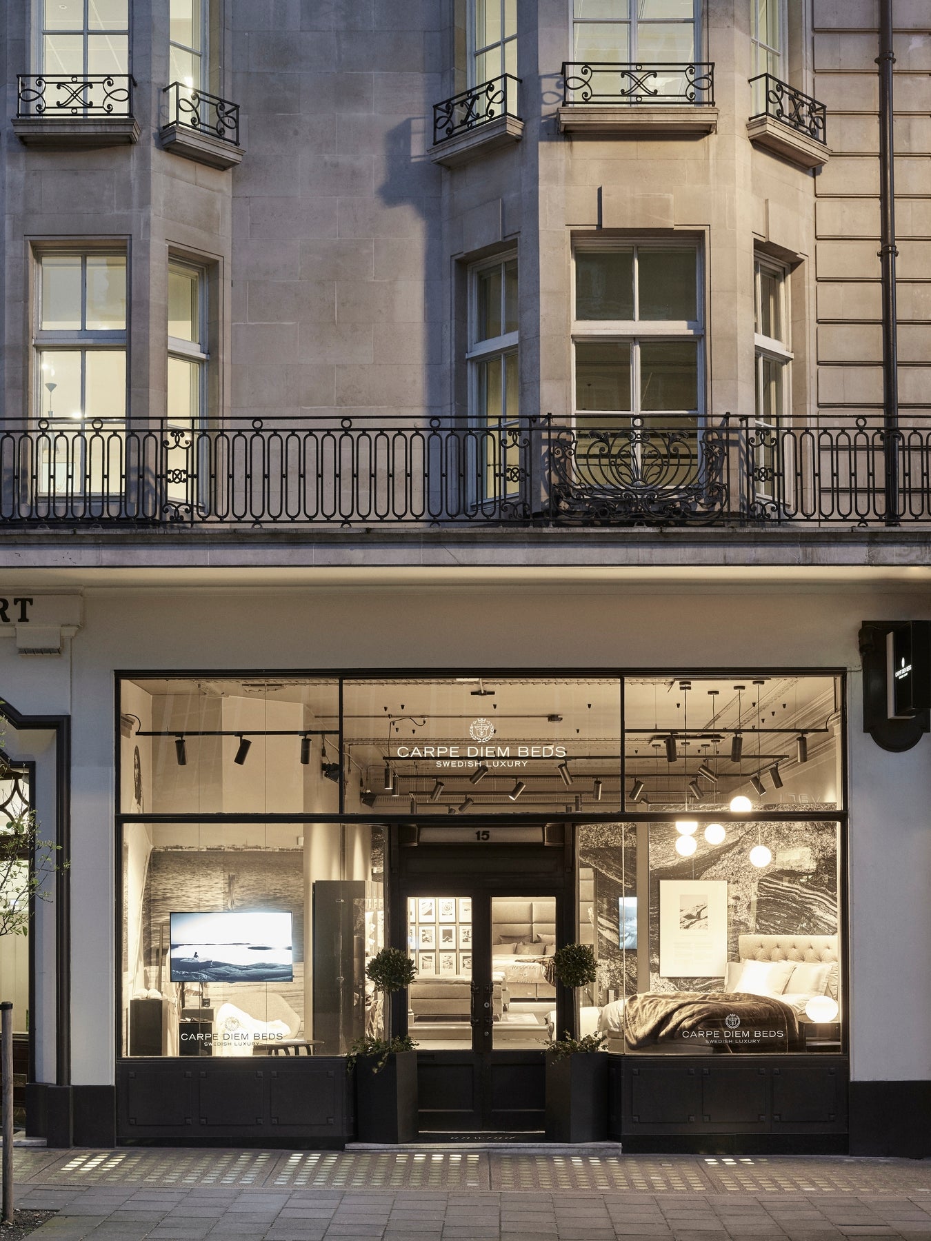 Storefront Carpe Diem Beds London. Modern building facade with large glass windows and a sign inside.